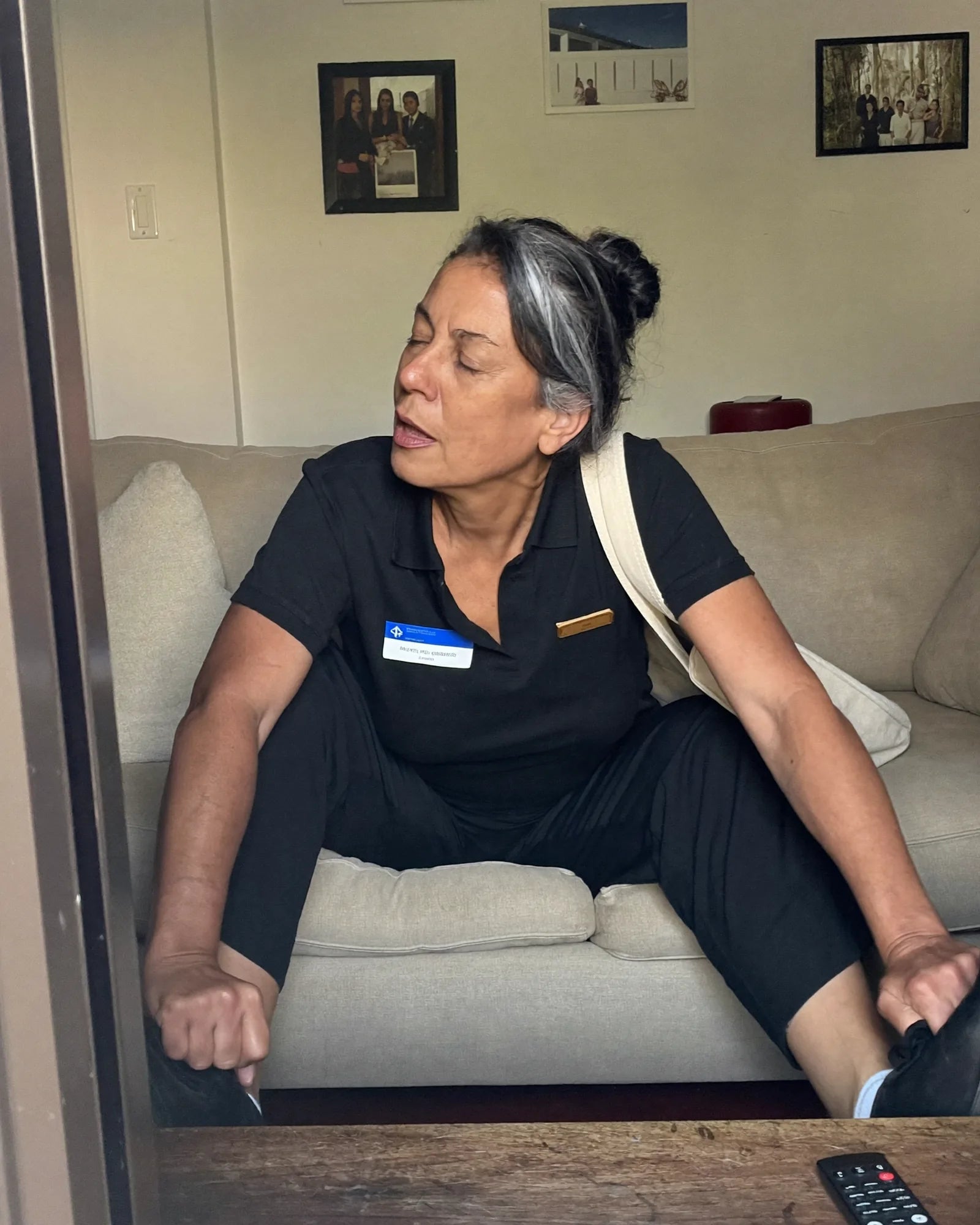Woman in a work polo dropping onto the couch after a shift