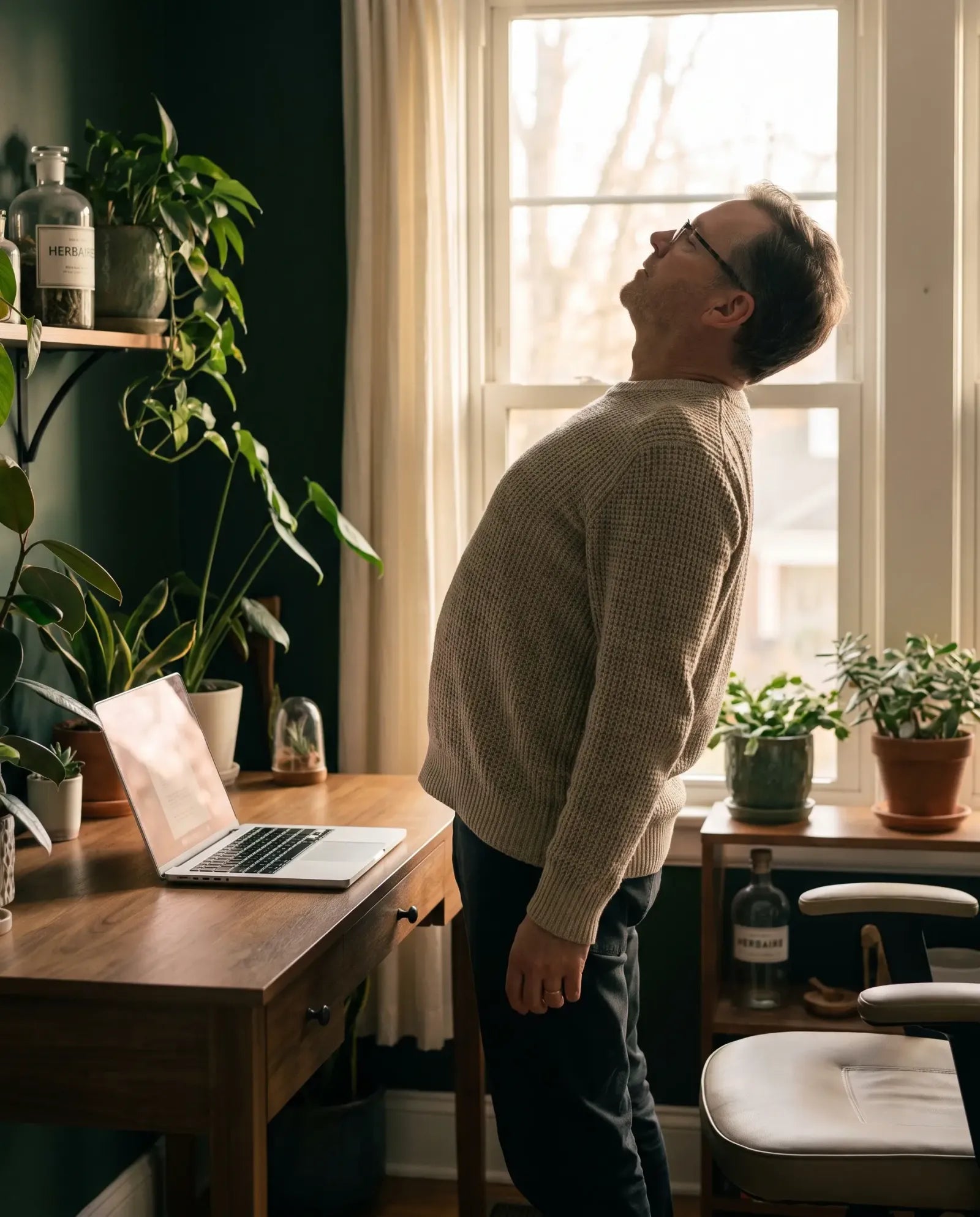 A man standing up from his desk to stretch