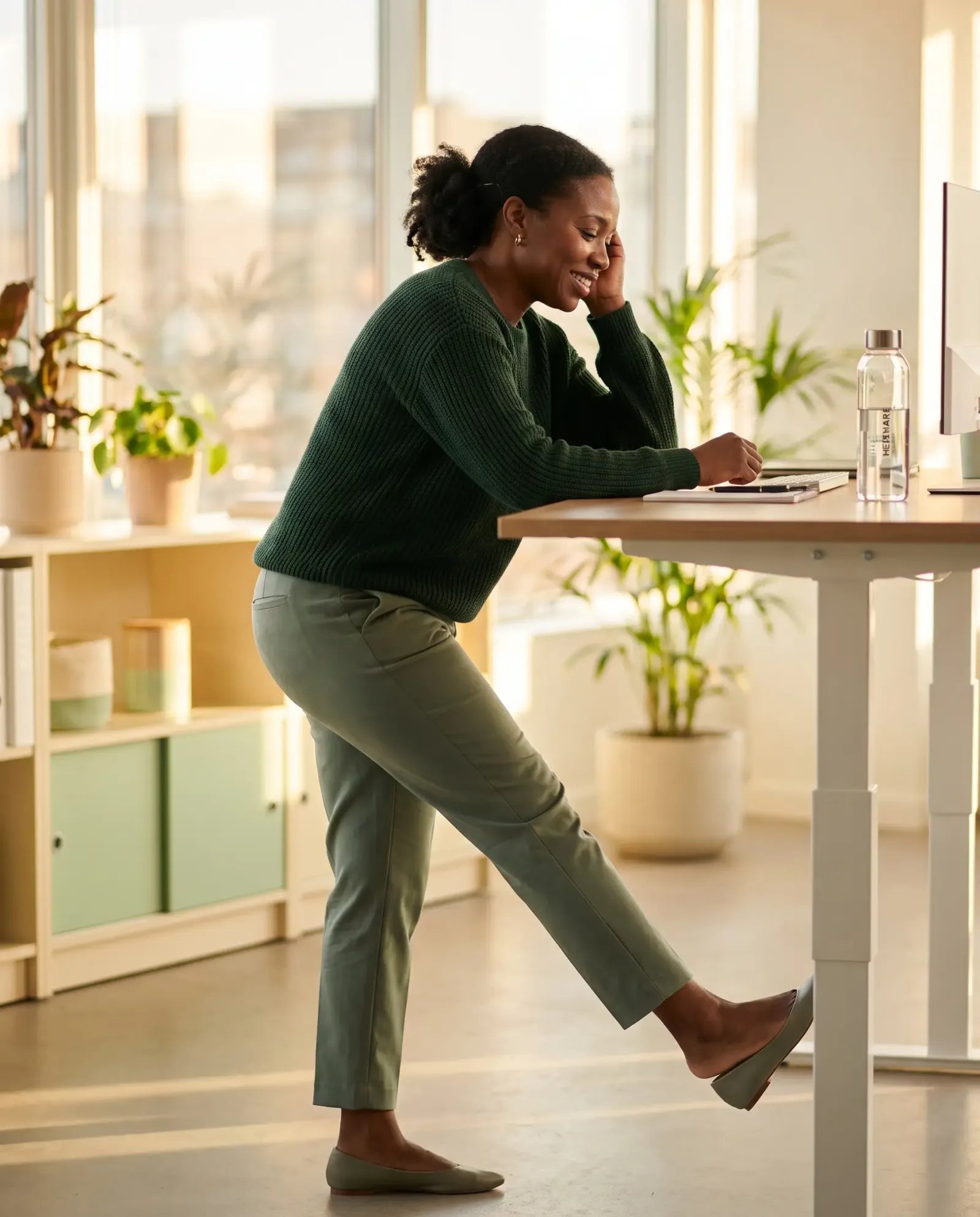 A woman stretching her leg at a standing desk at the end of the workday